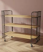 Three-tiered wooden shelf with metal frame against a pink wall